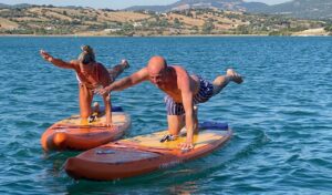 Pilates on paddle boards astern of catamaran Rush